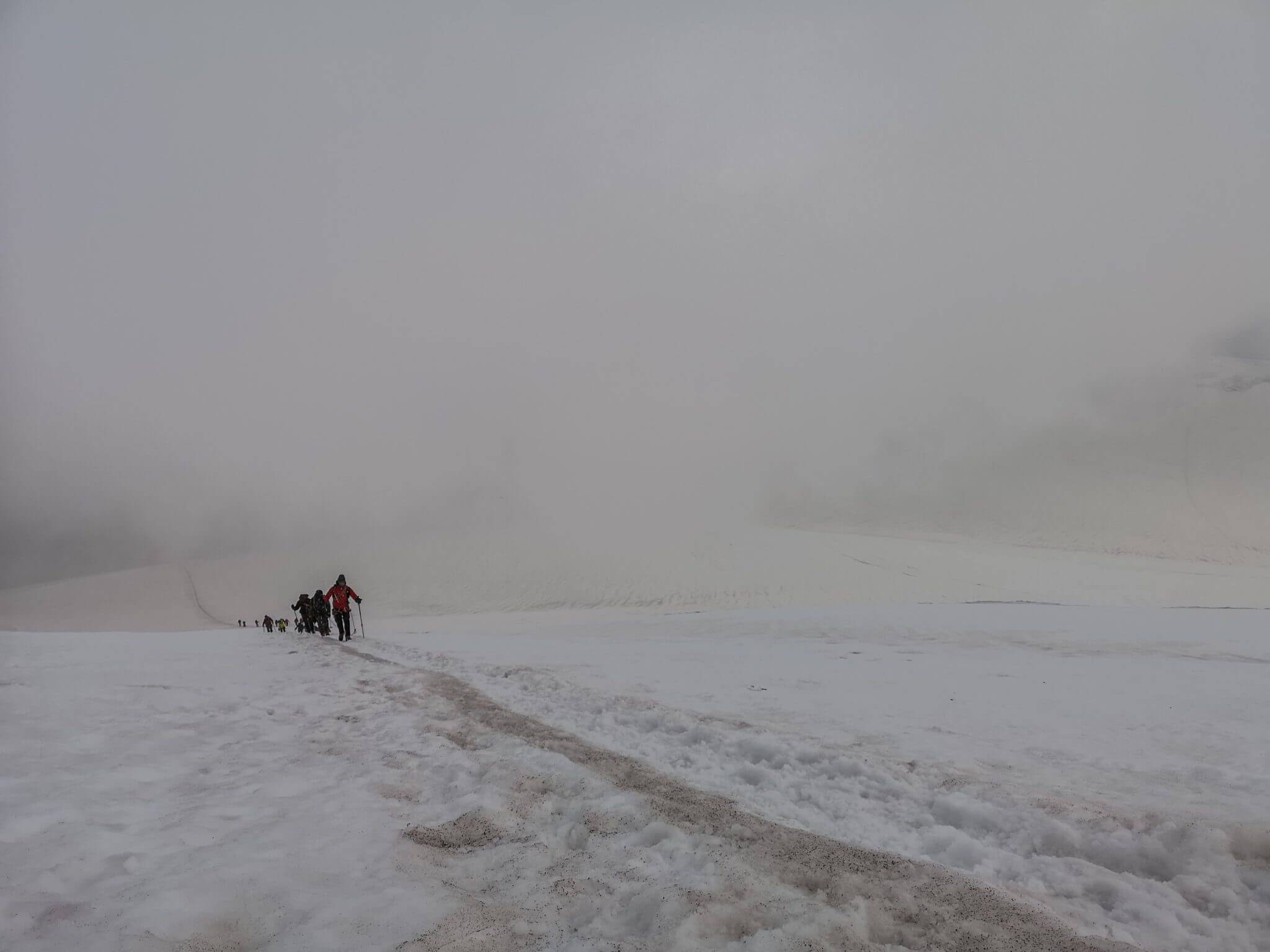 mountain climbers walking out of clouds
