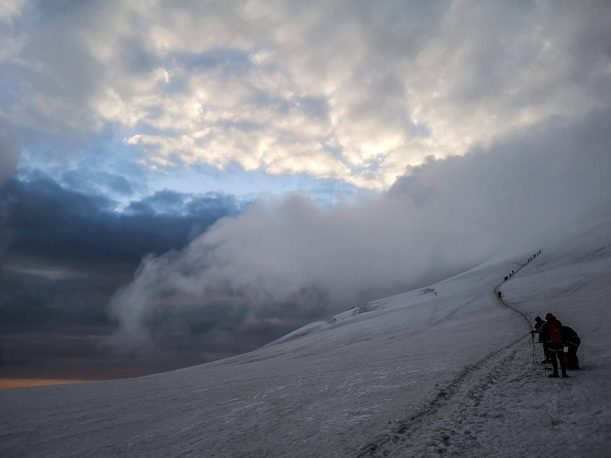 mountain climbers walking towards cloudy mountains