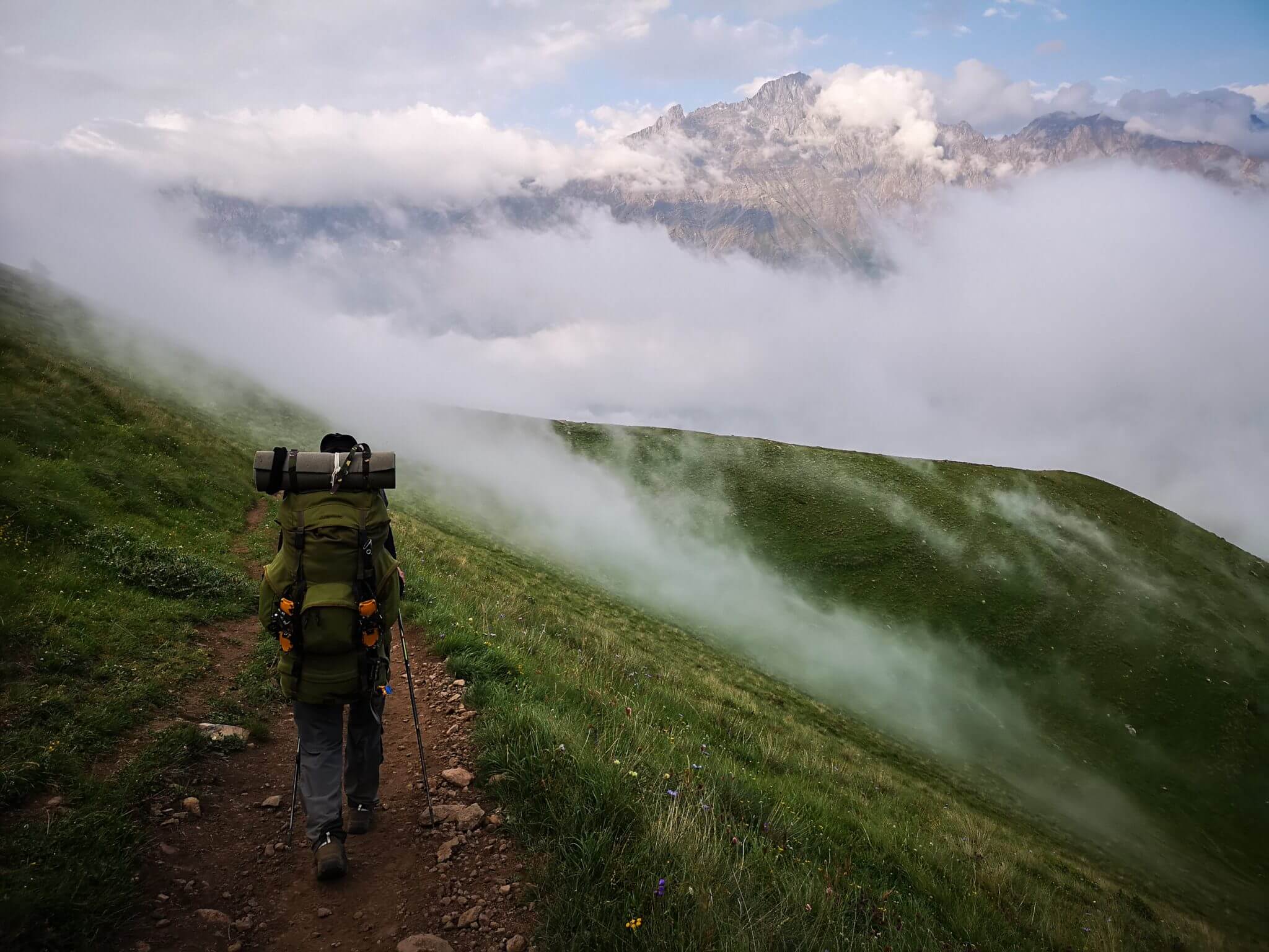 backpacker walking mountains clouds