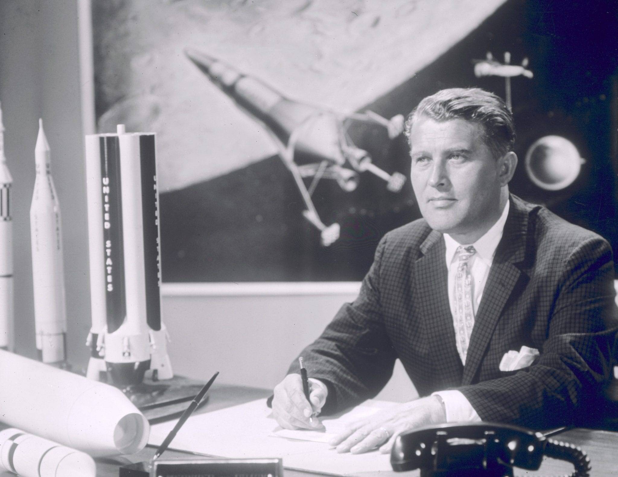 VON BRAUN, WERNHER-DR. IN HIS OFFICE WITH ROCKET MODELS BEHIND HIM