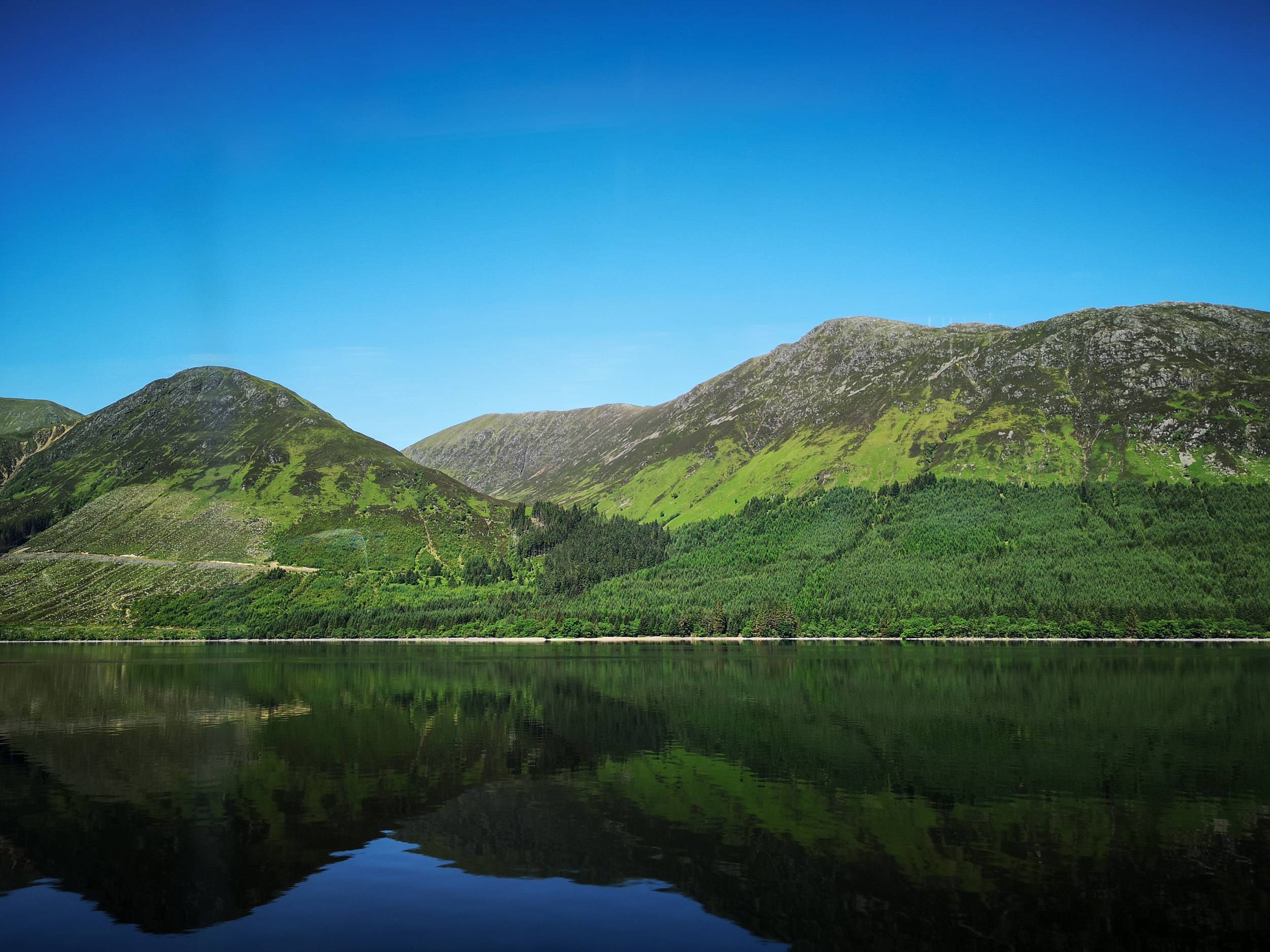 Mountains mirroring on loch in Highland of Scotland